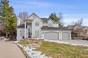 Traditional home with driveway, a shingled roof, a chimney, a front lawn, and brick siding