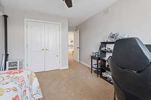 Bedroom with a closet, light colored carpet, visible vents, a ceiling fan, and baseboards