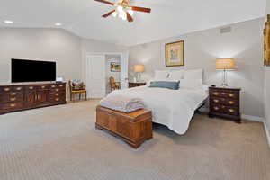 Bedroom featuring ceiling fan, light carpet, visible vents, baseboards, and vaulted ceiling