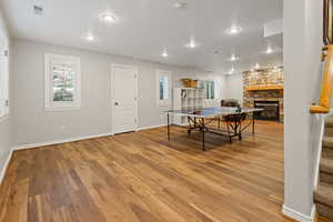 Recreation room with visible vents, a fireplace, baseboards, and wood finished floors