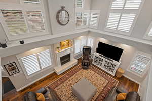 Living area with plenty of natural light, a fireplace, dark wood finished floors, and a towering ceiling