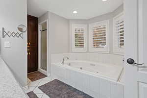 Bathroom featuring a stall shower, a tub with jets, and tile patterned floors