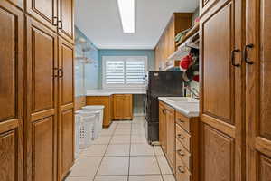 Kitchen with brown cabinets, light tile patterned floors, light countertops, and a sink