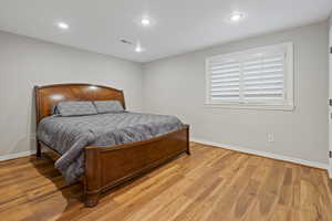 Bedroom with light wood-type flooring, visible vents, baseboards, and recessed lighting