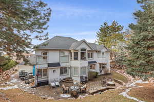 Rear view of property featuring a fire pit, a shingled roof, a patio area, and stucco siding