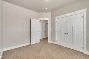 Unfurnished bedroom with baseboards, a closet, and light colored carpet