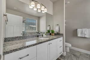 Full bathroom with toilet, baseboards, and vanity