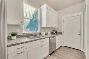 Kitchen featuring a sink, white cabinets, and stainless steel dishwasher