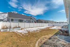 Rear view of house featuring a yard, a vegetable garden, a mountain view, a residential view, and a fenced backyard