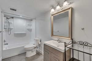 Full bath featuring a textured ceiling, toilet, shower / bath combination, vanity, and visible vents