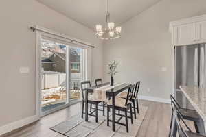 Dining room featuring light wood-style floors, baseboards, and an inviting chandelier