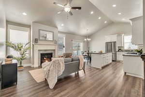 Living area featuring ceiling fan with notable chandelier, recessed lighting, dark wood-style flooring, and a premium fireplace