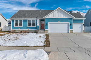 View of front facade with a shingled roof, concrete driveway, an attached garage, a mountain view, and board and batten siding