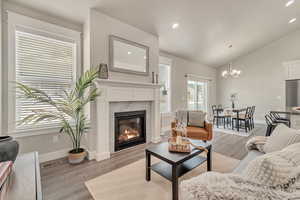 Living area with visible vents, lofted ceiling, light wood-style flooring, a fireplace, and recessed lighting