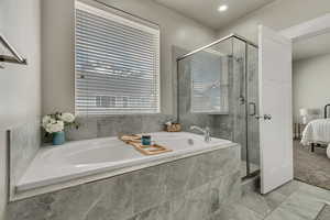 Ensuite bathroom featuring marble finish floor, a garden tub, a shower stall, and ensuite bathroom