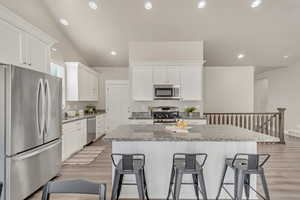 Kitchen with white cabinetry, a kitchen bar, appliances with stainless steel finishes, and a center island