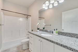 Bathroom with toilet, tile patterned floors, bathtub / shower combination, and vanity