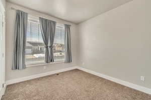 Spare room featuring carpet floors, visible vents, and baseboards