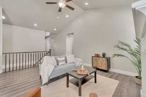 Living area featuring high vaulted ceiling, recessed lighting, wood finished floors, and baseboards