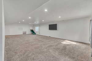 Interior space featuring a textured ceiling, recessed lighting, light colored carpet, and baseboards