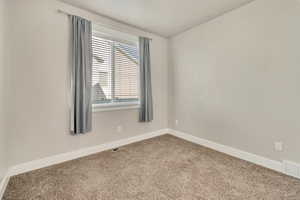 Empty room with carpet flooring, visible vents, and baseboards