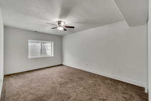 Carpeted empty room featuring visible vents, ceiling fan, a textured ceiling, and baseboards