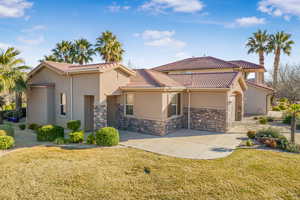 Mediterranean / spanish-style house featuring a front lawn, a tile roof, and stucco siding