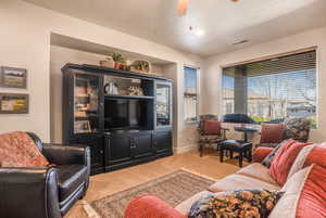 Living area with light carpet, a ceiling fan, visible vents, and baseboards