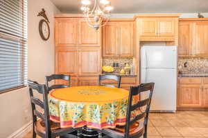 Dining space with light tile patterned floors, baseboards, and an inviting chandelier