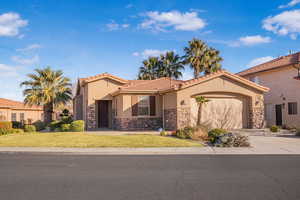 Mediterranean / spanish-style home featuring a tile roof, stucco siding, concrete driveway, a garage, and stone siding