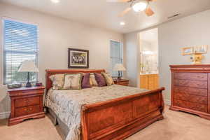 Bedroom featuring light carpet, baseboards, visible vents, ensuite bath, and recessed lighting