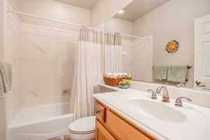 Bathroom with shower / bath combination with curtain, vanity, and toilet