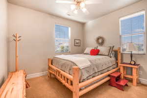 Bedroom with a ceiling fan, light carpet, and baseboards