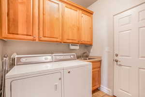 Washroom featuring light tile patterned floors, a sink, baseboards, independent washer and dryer, and cabinet space