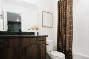 Bathroom with shower / bath combination with curtain, vanity, and toilet