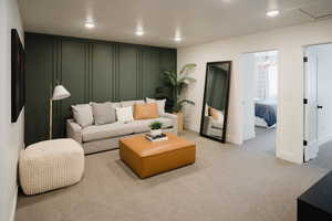 Living room featuring recessed lighting, a decorative wall, and light colored carpet