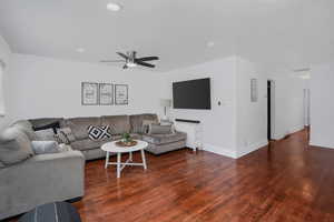 Living area featuring dark wood finished floors, visible vents, and baseboards