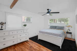 Bedroom featuring beam ceiling, ceiling fan, baseboards, and wood finished floors