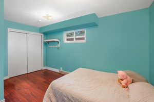 Bedroom featuring dark wood-style floors, baseboards, and a closet