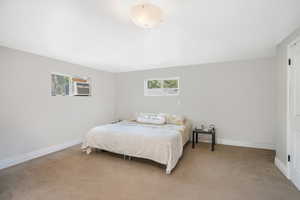 Bedroom with light carpet, baseboards, and multiple windows