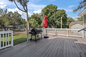 Wooden deck featuring a trampoline, grilling area, and a yard