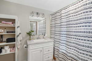 Full bathroom featuring curtained shower and vanity