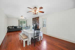 Dining room featuring a brick fireplace, dark wood finished floors, visible vents, and baseboards