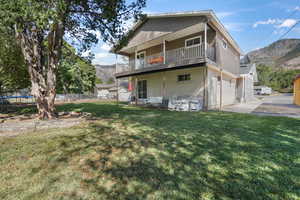 Back of property with a garage, a trampoline, a mountain view, and a lawn