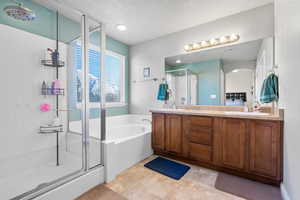 Full bath featuring double vanity, a garden tub, a shower stall, and a sink