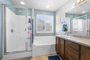 Full bath featuring a stall shower, a garden tub, and vanity