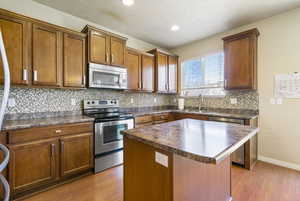 Kitchen with a sink, stainless steel appliances, dark countertops, and a kitchen island