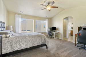 Bedroom with light carpet, visible vents, arched walkways, baseboards, and lofted ceiling