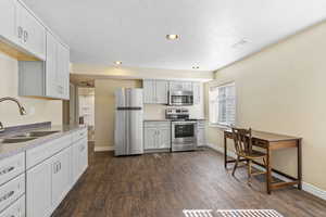 Kitchen with light countertops, appliances with stainless steel finishes, a sink, and white cabinetry