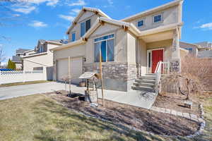 View of front of home featuring stucco siding, an attached garage, fence, stone siding, and driveway